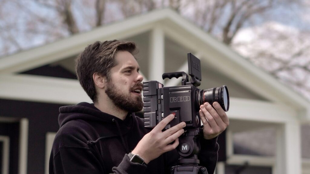 A filmmaker adjusts a professional cinema camera during an outdoor shoot.