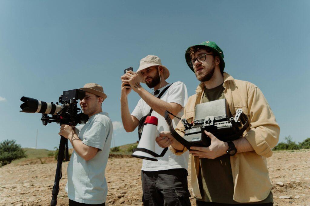 Three men with cameras and equipment shooting a film outdoors.