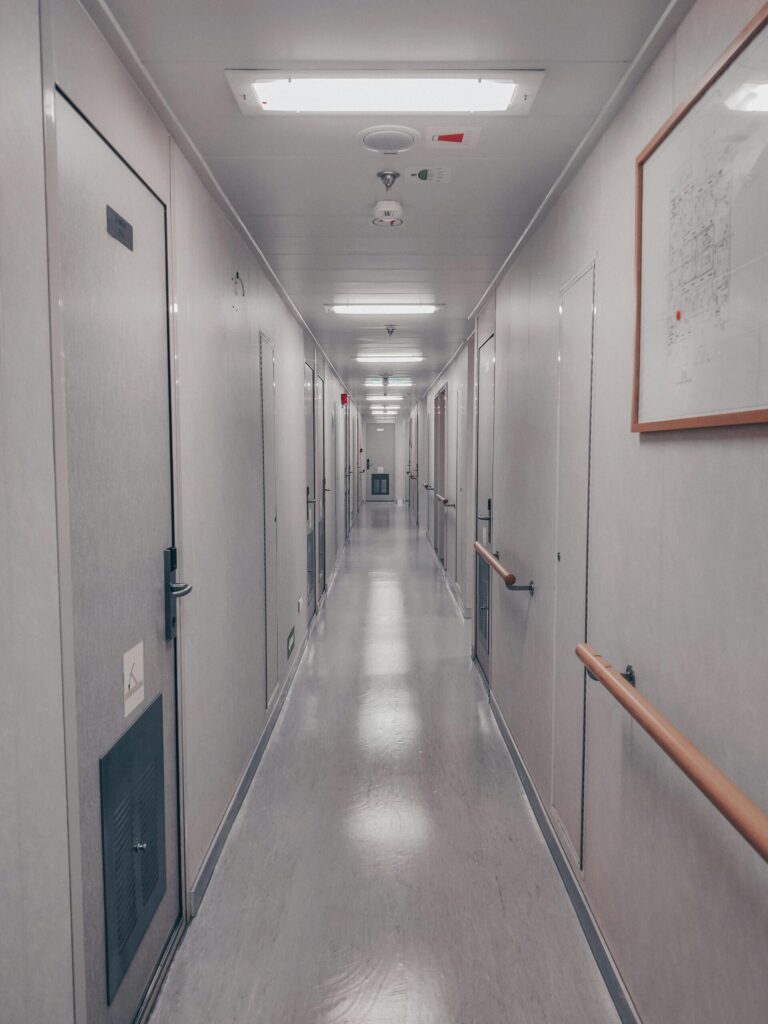 A well-lit industrial hallway with multiple doors and handrails in Ras Laffan, Qatar.